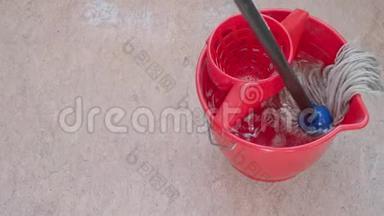 拖把在桶里冲洗，清洁粉红色油毡地板